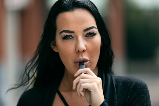 Adult Female Inhaling Vapor With An E-Cigarette