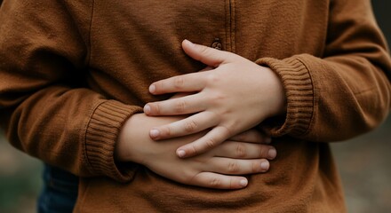 Child Holding Stomach with Brown Sweater Close-up