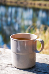 a cup of coffee on wooden table in the forest