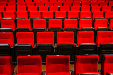 Rows of red seats in an auditorium or cinema hall. Evokes entertainment, leisure, and culture.