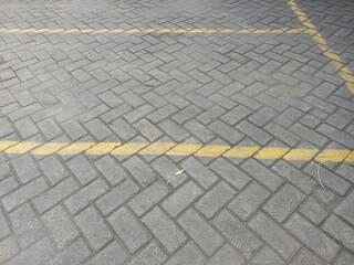 Fototapeta premium Gray Paving Stones with Yellow Parking Lot Lines