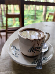 A cup of hot black coffee, served in a cafe with a nature theme.