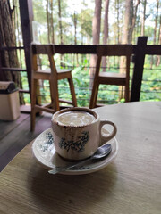 A cup of hot black coffee, served in a cafe with a nature theme.