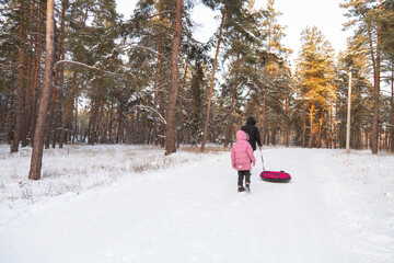 Father and daughter having fun with snow tube in the forest