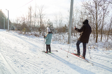 Dad and daughter skiing in the winter forest