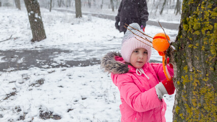 Child walking in the snow park enjoys the first snow in winter