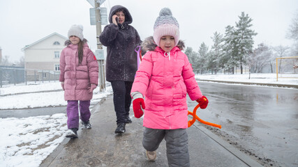 Grandmother with grandchildren in warm clothes playing outdoors in winter park, enjoying snowy...