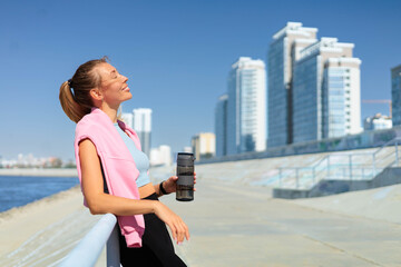 Sport woman jogger runner drinking water from bottle at city embankment river closeup