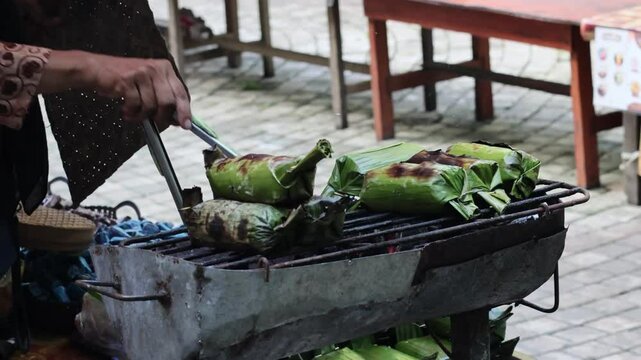 Process Baking Gogos on the grill, Gogos is a typical food from the Indonesia made from white sticky rice mixed with coconut milk and filled with fish, then wrapped in banana leaves and grilled.