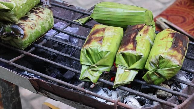 Process Baking Gogos on the grill, Gogos is a typical food from the Indonesia made from white sticky rice mixed with coconut milk and filled with fish, then wrapped in banana leaves and grilled.