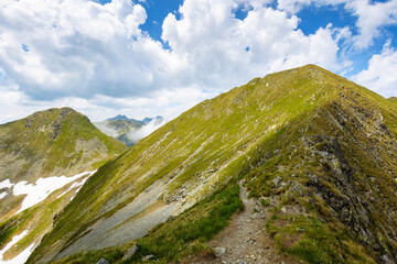 steep slopes of faragas mountain ridge in summer. hiking trail path through wonderful transylvania alps. blue sky with fluffy clouds