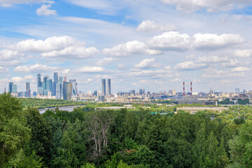 Scenic view from Vorobyovy Gory over Moscow River, lush green trees, and clouds in the blue sky. The natural beauty of Moscow River complements the city skyline in the background