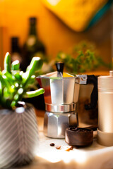 Ingredients for making coffee. Moka coffee maker, coffee grinder with coffee beans are on the table of a cozy kitchen.