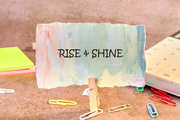 Growth Success Achievement Progress Concept. Words RISE AND SHINE written on paper, fixed in a...
