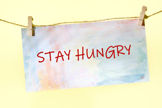 Concept Phase STAY HUNGRY written on a colorful sign on a rope with clothespins - Powered by Adobe