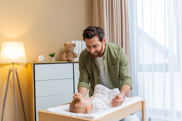 Young caucasian man changing diaper to his little baby boy