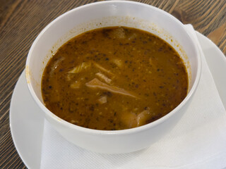 Traditional Slovak tripe soup (držková polievka) served in a white bowl on a wooden table, rich reddish broth with visible beef tripe pieces.