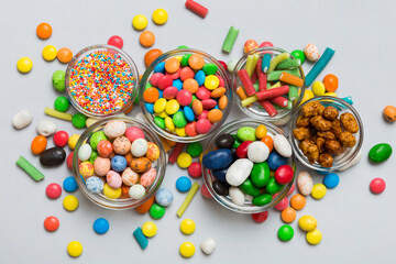 different colored round candy in bowl and jars. Top view of large variety sweets and candies with copy space
