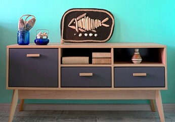 Chest of drawers with marine items and a picture of a fish. Marine style in the interior of the room