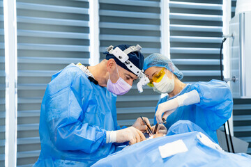 Surgeons in the operating room. Surgeons concentrate on a patient in a bright, modern operating...