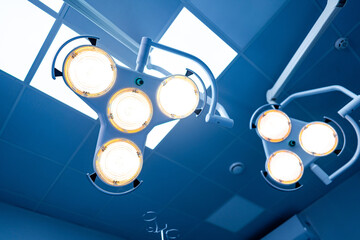 Surgical lights bright the OR. Bright surgical lights hang from the ceiling, ensuring a well-lit...