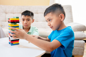 Children carefully playing colorful stacking tower game at home