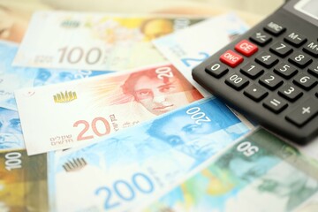 Israel New Shekels banknotes and calculator. The current Israel money bills and calc lies on table