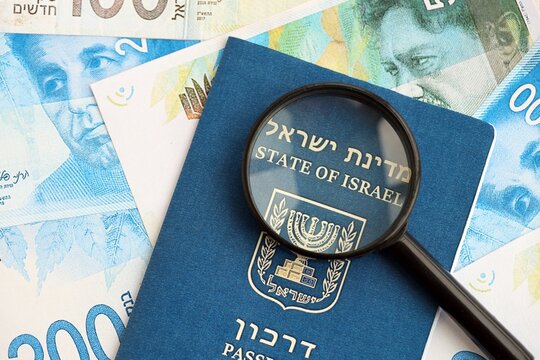 Israel New Shekels banknotes and passport with loupe. The current Israel money bills and pass
