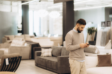 Man Using Smartphone While Shopping for Furniture in Modern Store Interior