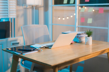A well-lit, modern office space features a wooden desk with a laptop, tablet, and plant, suggesting a calm and productive work environment. Colorful notes add a touch of personality.