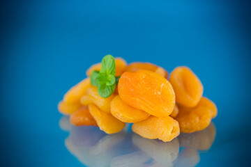 Isolated dried apricots with green mint on a bright blue background