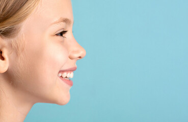 Close-up of the profile of the child smiling lovingly against the teal color background.