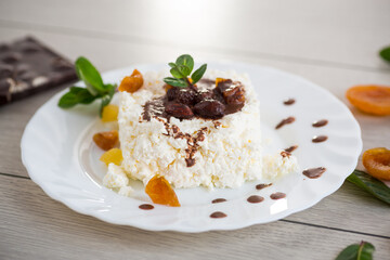Healthy cottage cheese dessert with dried apricots, candied fruits and chocolate syrup