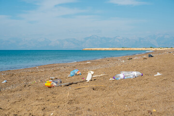 Discarded plastic bottles and cup littering the beach near the shoreline