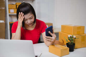 An Asian woman in a light red T-shirt is selling goods online, efficiently packing orders for...