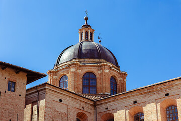 The Ducale Palace, an iconic symbol of Urbino, highlights intricate brickwork and elegant domes. This architectural marvel reflects the city's rich history. Urbino, Marche, Italy