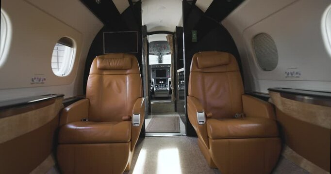 Brown leather seats in cabin of luxury private aircraft facing flight deck