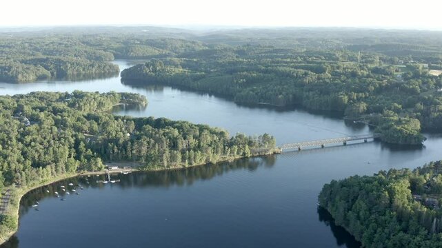Aerial view of vast lake system with Pont de Lantourne bridge, surrounded by dense forests, Marcillac La Croisille, France