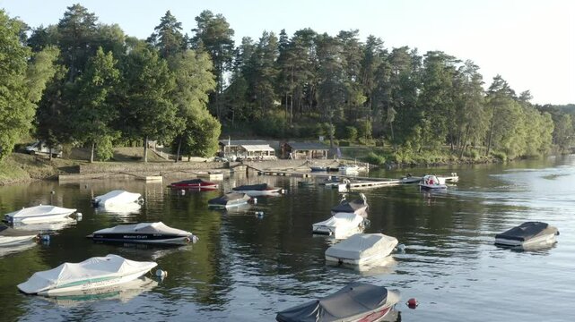 Aerial view of numerous small boats moored on calm lake by forested shore, recreational area, Marcillac La Croisille, France