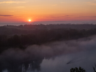 Fototapeta premium Aerial View of Sunrise and Morning Mist Over a Lowland Forest Landscape