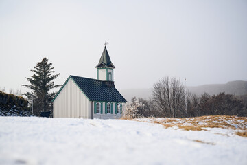 Small white church standing on snowy hill in winter landscape