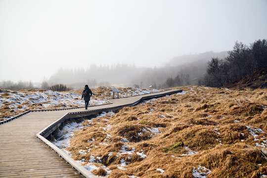 Tourist walking on wooden footbridge in winter landscap