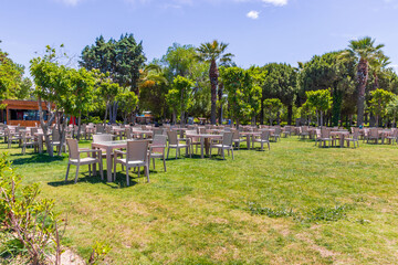 Aliaga, Turkey - May 28, 2025: tropical park with palm trees and green grass under a blue sky. Ideal for vacation, travel background, and relaxation themes.