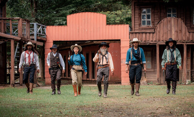 Group of cowboys and cowgirl wearing 19th-century American frontier cowboy hats, vests, boots,...