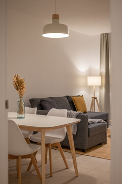 View of dining area and living room with white table, blue vase centerpiece, gray sofa and floor lamp