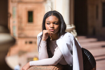 Portrait of young, beautiful, African woman, wearing leather jacket and shorts, with her hand on...