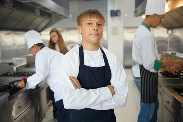 Obraz premium portrait young man chef crossed arms pose in the kitchen