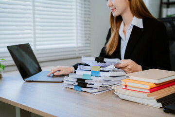 Cropped shot of busy businesswoman sorting through cluttered documents and folders. Completed and...