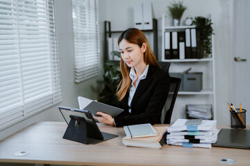 Closeup image of businesswoman writing on notebook while working on laptop in office