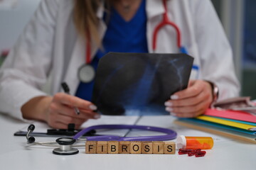 A doctor is meticulously reviewing an Xray to diagnose fibrosis, surrounded by essential medical...